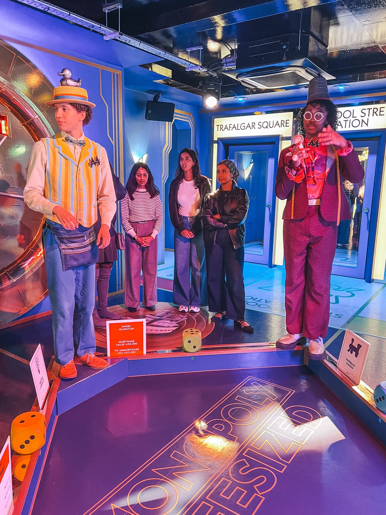 Players standing on the lifesized Monopoly board with two costumed hosts at Monopoly Lifesized London