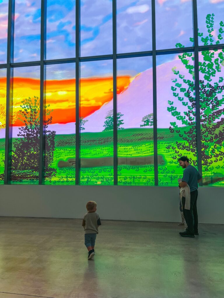 Toddler walking towards a huge colourful digital landscape artwork at Turner Contemporary in Margate
